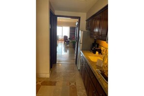 Kitchen features a stainless steel refrigerator, sink, and granite countertop, with a doorway leading to a dining area.