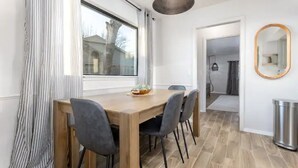 A dining area with a wooden table and four chairs, a window with curtains, and a mirror on the wall. - Clean and Updated Home in Moore with Bonus Room  (Moore)