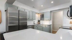 A modern kitchen with stainless steel appliances, light gray cabinets, and a central island. - Clean and Updated Home in Moore with Bonus Room  (Moore)