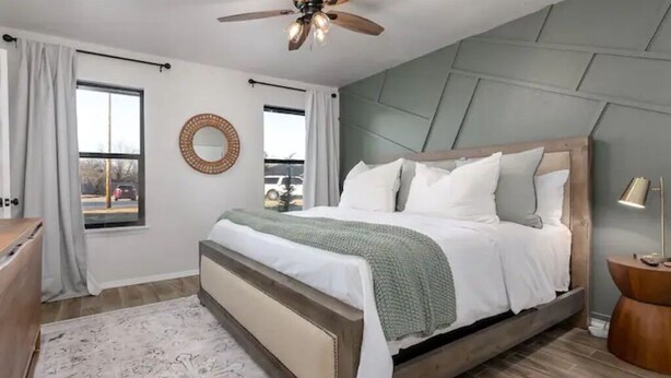 A modern bedroom with a large bed, a ceiling fan, and a view of the outside through a window. - Clean and Updated Home in Moore with Bonus Room  (Moore)