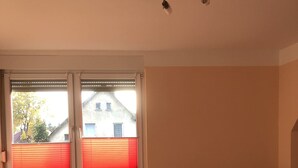 Een slaapkamer met een bed, een radiator, een raam met zonwering en een plafondventilator.