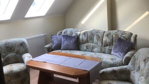 Een gezellige kamer met een schuine kap, een bank, een houten tafel en een radiator.