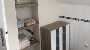 Een hoek van een kamer met een houten kast en planken met opgevouwen handdoeken.