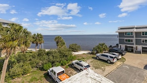 A coastal hotel with a parking area, a view of the sea, and a building with a flat roof. - Corner View at Cedar Cove! Gulf View Downtown! (Cedar Key)