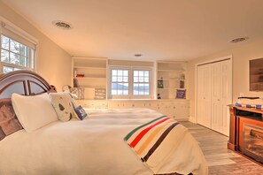A bedroom with a large bed, built-in shelving, a fireplace, and a view of the outdoors. - Finger Lakes Vacation Rental w/ Hot Tub & Pool (Naples)