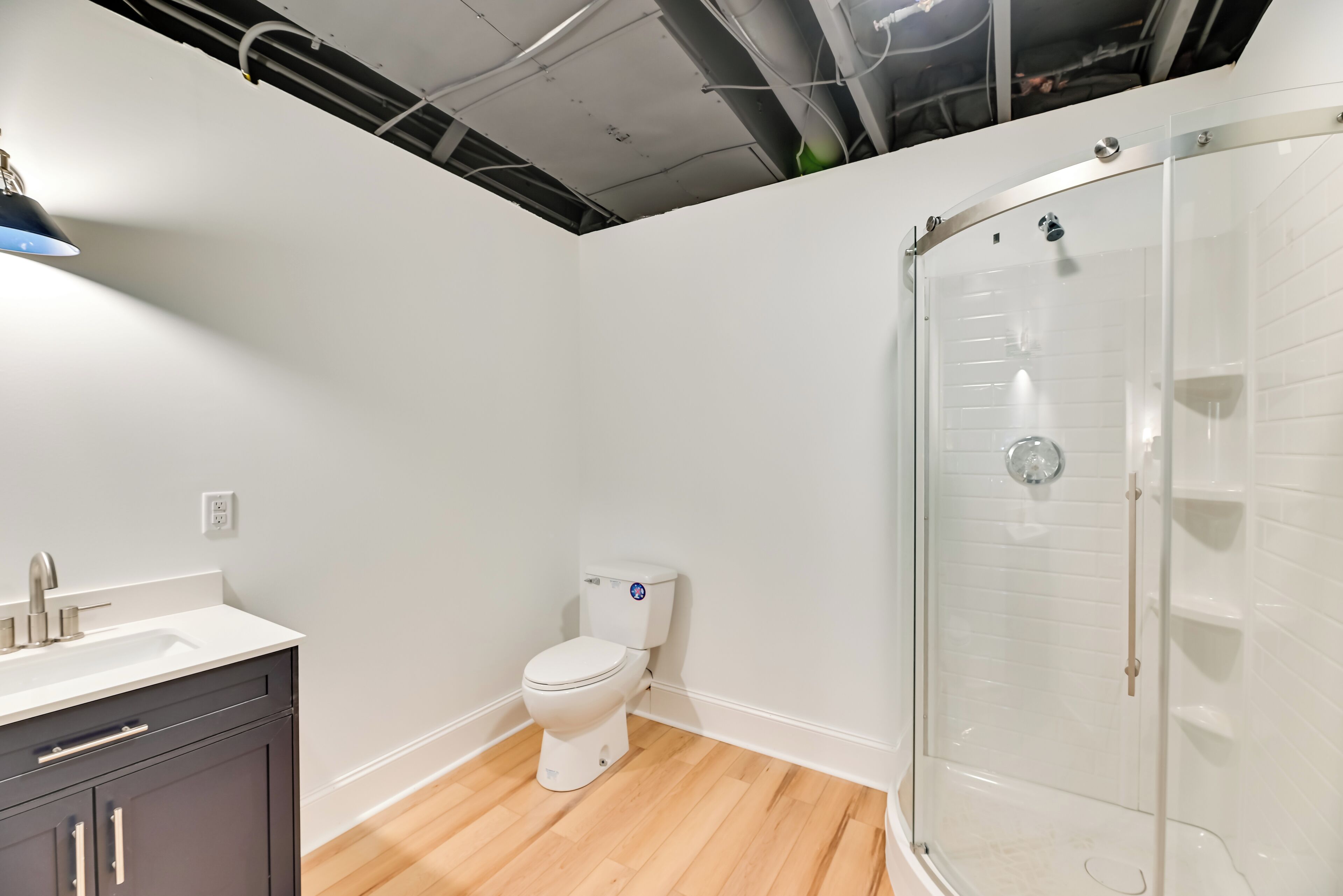 Une salle de bain moderne équipée de toilettes, d’un lavabo et d’une douche à parois de verre.
