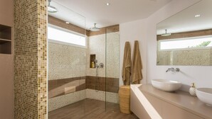 Een moderne badkamer met een douchecabine van glas, een grote spiegel en een wastafel met twee wasbakken.