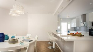 Een moderne keuken met witte kasten, een centraal eiland met barkrukken en hanglampen.