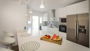 Een moderne keuken met witte kasten, roestvrijstalen apparatuur en een centraal eiland met fruit.