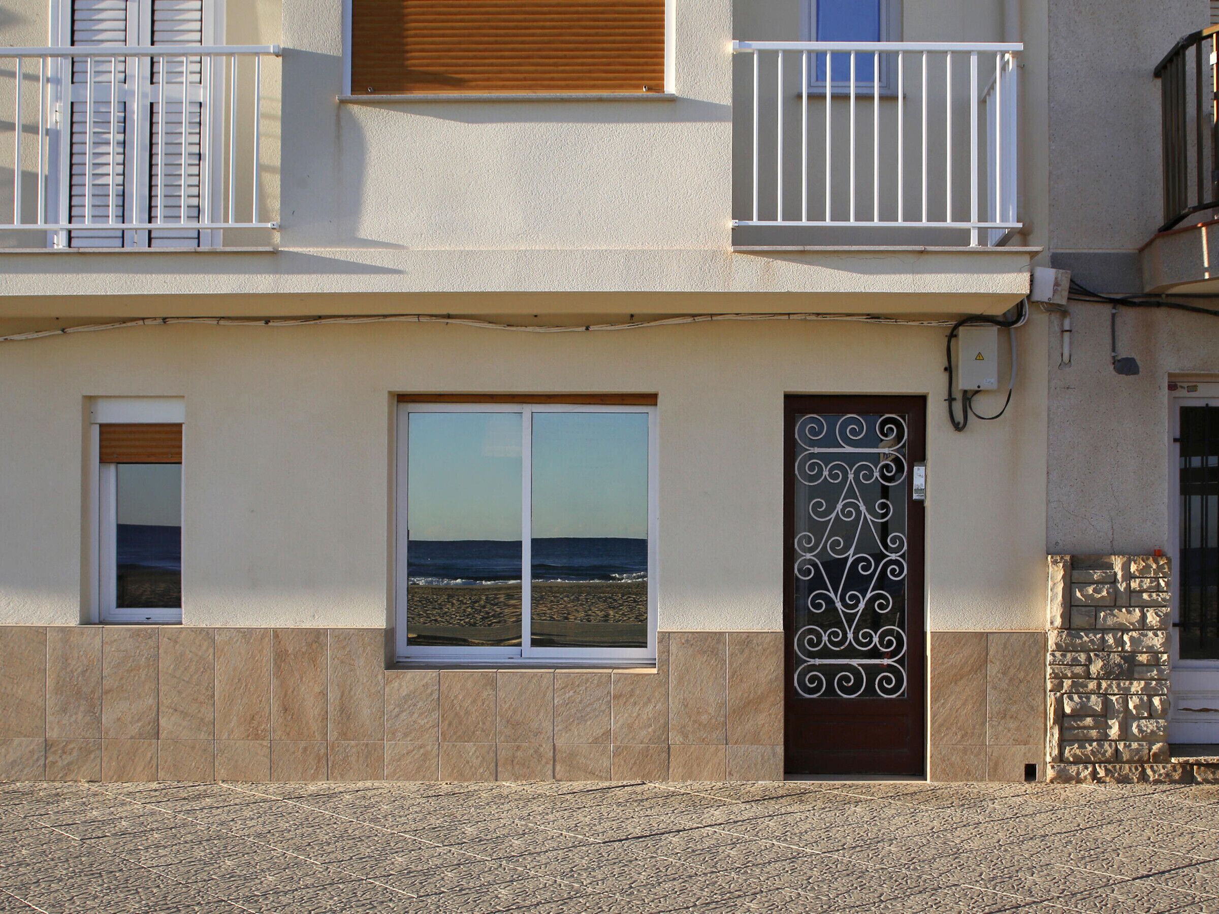 Een gebouw met balkon, groot raam en decoratieve metalen poort.