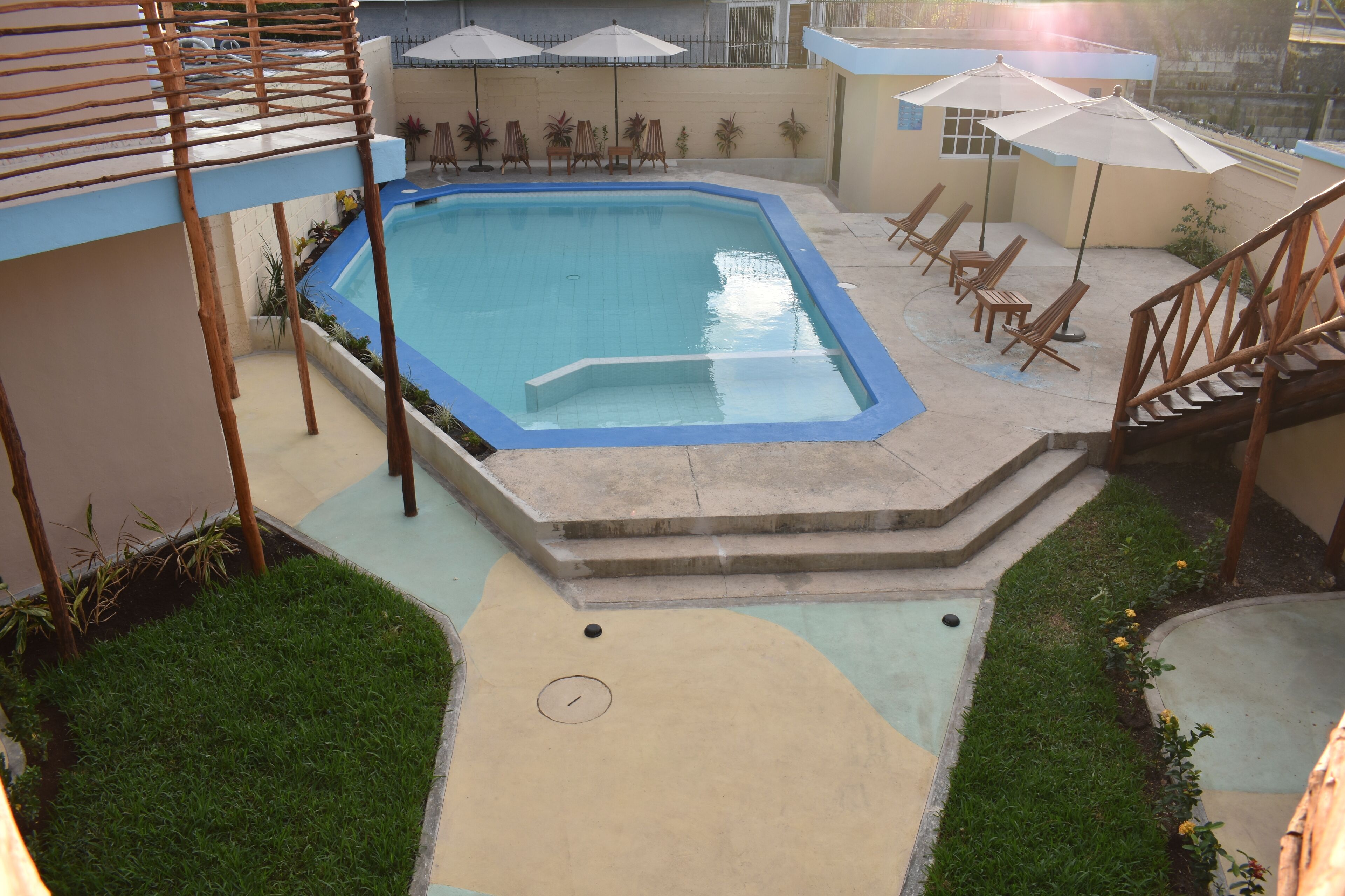 Una piscina con cubierta de madera, sillas de descanso y sombrillas.