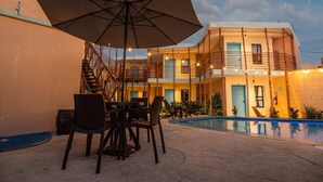 An outdoor seating area with a table, chairs, and a large umbrella. - Luna Azul by Uvas (Cozumel)