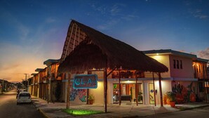 A hotel with a thatched roof, a signboard, and potted plants. - Luna Azul by Uvas (Cozumel)
