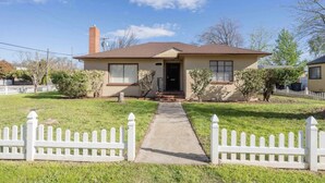 A single-story house with a front porch, a chimney, and a small front yard.