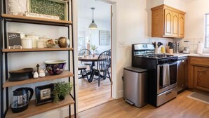 A modern kitchen with wooden cabinets, a stainless steel stove, and a dining area with a table and chairs.