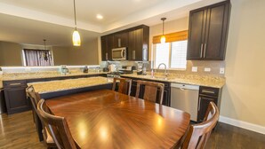 A modern kitchen with dark cabinetry, granite countertops, and a central island with seating.