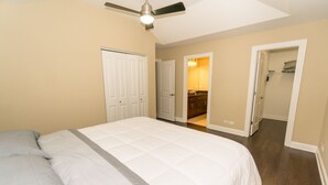 A bedroom with a bed, a ceiling fan, and a bathroom visible through an open door.