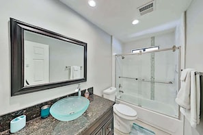 A bathroom with a large mirror, a glass sink, a toilet, and a glass-enclosed shower. - Luxe Retreat - Backyard Oasis (Palm Springs)