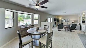 A modern kitchen with a dining area, large windows, and a ceiling fan. - Luxe Retreat - Backyard Oasis (Palm Springs)