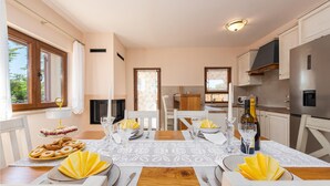 A dining area with a table set for four, a kitchen with modern appliances, and a fireplace.