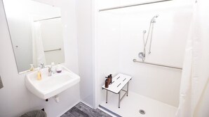 Un baño con lavamanos blanco, espejo y ducha.
