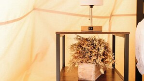 Una mesita de noche de madera con una lámpara y un jarrón de flores secas.