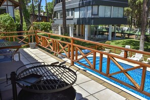 A poolside area with a barbecue grill, lounge chairs, and a view of a pool. - suites del bosque (Pinamar)