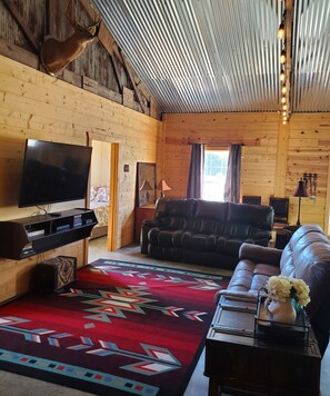 A cozy cabin interior with a wooden interior, a television, a leather sofa, and a patterned rug. - House on Mount Magazine (Paris)
