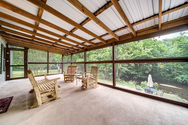 Amplia habitación con ventanas grandes, muebles de madera y vista a un estanque.