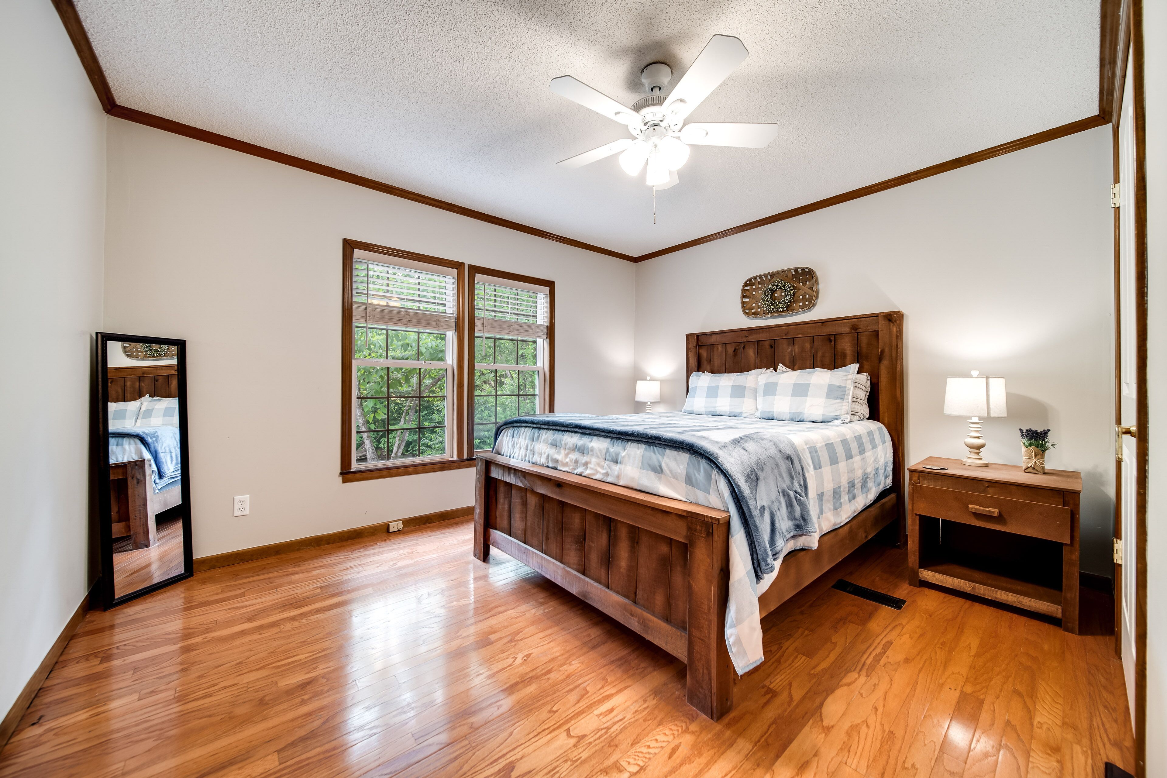 A bedroom with a wooden bed, a nightstand, a ceiling fan, and a window with blinds.