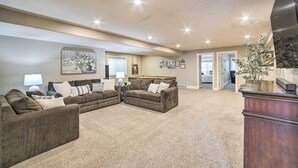 A spacious living room with a large sectional sofa, a flat-screen TV, and a decorative plant. - Spacious Idaho Home: Ski, Hike, & Fish! (Rexburg)
