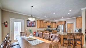A spacious kitchen with wooden cabinets, a dining table, and a large island with bar stools. - Spacious Idaho Home: Ski, Hike, & Fish! (Rexburg)