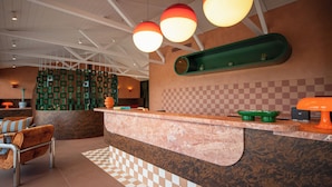 A reception area with a checkered floor, a reception desk, a green shelf, and a hanging light fixture. - The Monty (Anglesea)