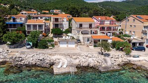 Un pueblo costero con aguas cristalinas, edificios de piedra y un litoral rocoso.