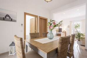 Enjoy meals in this stylish dining area with a large table for four, a beautiful painting, and a vase with fresh flowers.