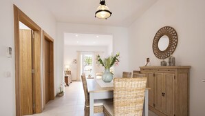 A dining area with a wooden cabinet, wicker chairs, a table, and a hanging light fixture. - 3 bedroom house near the sea (Can Picafort)