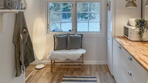 A compact kitchen with a window, a microwave, a fan, and a bench with cushions. - 3 bedroom beautiful home in Markaryd (Markaryd)