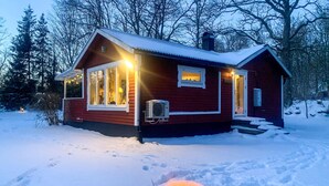 A cabin with a snow-covered roof, a fire pit in the front, and a window with a view of the forest. - 3 bedroom beautiful home in Markaryd (Markaryd)