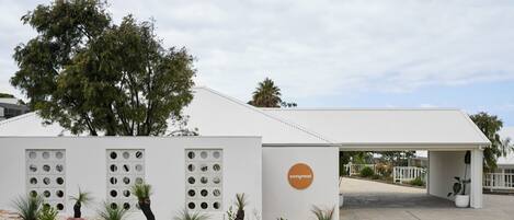 A building with a white exterior, a circular logo, and a covered entrance area.
