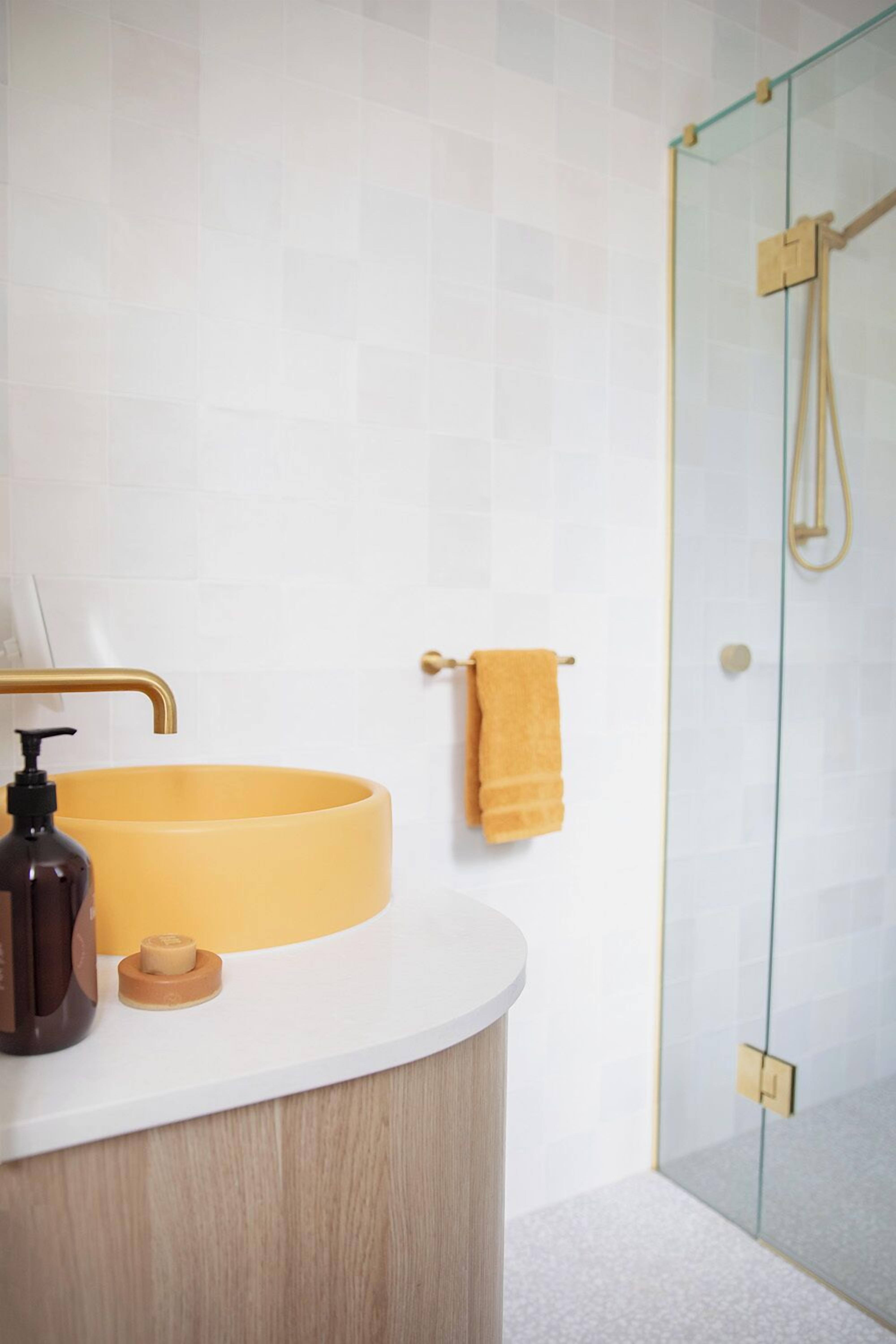 A bathroom with a round sink, a wooden vanity, a glass shower enclosure, and a towel rack.