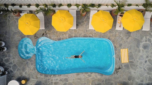 Una piscina al aire libre, sombrillas, tumbonas