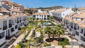 A hotel with multiple floors, a central courtyard with a pool, palm trees, and a view of the surrounding area. - El Sembrador | Pool - terrace - pool table (La Cala de Mijas)