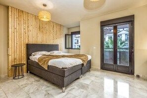 Ein Schlafzimmer mit Bett, einem kleinen Tisch, einer Holzvertäfelung, einem großen Fenster und einer Tür.