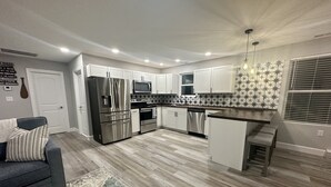 A modern kitchen with white cabinets, stainless steel appliances, and a patterned backsplash.