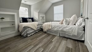 A bedroom with two beds, a ceiling fan, and built-in shelving.