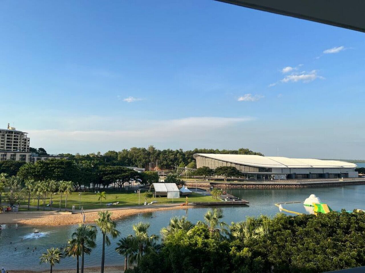 Une vue sur le fleuve, avec un bâtiment moderne, une plage et des palmiers.