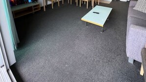 Un espace de vie compact comprenant un téléviseur, une table à manger, des chaises, un coin cuisine et un canapé.
