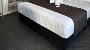 Una camera d'albergo con un letto, un armadio, un comodino e un condizionatore d'aria.