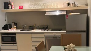 Una cucina moderna con microonde, macchina del caffè e lavastoviglie. C'è un tavolo da pranzo con un vaso di fiori.