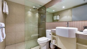 A modern bathroom with a glass-enclosed shower, a white toilet, and a sink with a mirror above it.